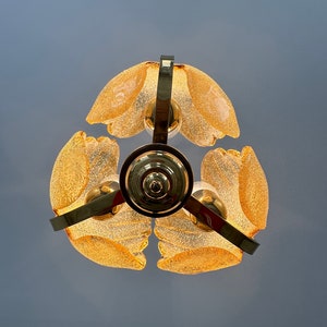 May include: A gold-toned chandelier with four frosted glass shades. The shades are shaped like petals and have a textured surface.