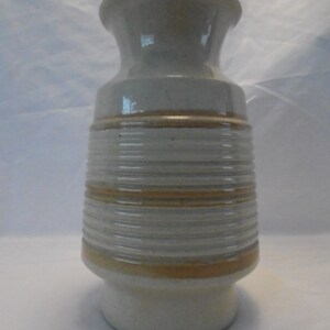 May include: A white ceramic vase with brown stripes. The vase has a wide mouth and a narrow base.