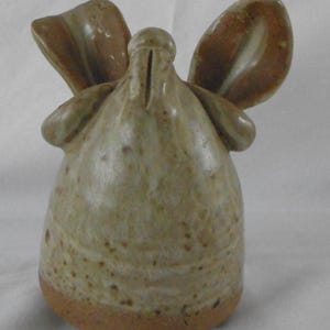 May include: A ceramic figurine of a bird with wings outstretched. The bird is light brown with white and brown speckles. The figurine is about 6 inches tall.