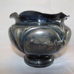 May include: A silver bowl with a scalloped rim and intricate floral designs. The bowl has a round base and a slightly flared opening.