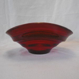 May include: A deep red glass bowl with a fluted design. The bowl is made of clear glass and has a shiny finish.