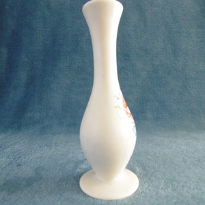 Pode incluir: Vaso de cerâmica branco com um design floral em tons de vermelho, azul e verde. O vaso tem um pescoço estreito e uma base larga.