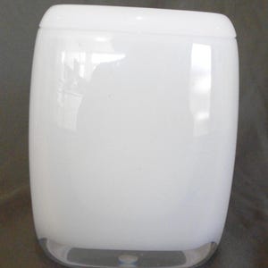May include: A rectangular white glass vase with rounded corners and a smooth, glossy finish. The object features a thick, clear glass base that provides a subtle contrast to the opaque white body, creating a clean and simple aesthetic design.
