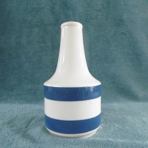 May include: A white ceramic vase with blue horizontal stripes. The vase has a narrow neck and a wide base.