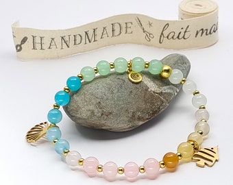 Bracelet pour femme avec perles colorées blanches, vertes, roses et bleues avec pendentifs dorés en forme de poisson tropical et coquillage