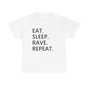 Puede incluir: Camiseta blanca con el texto negro "EAT. SLEEP. RAVE. REPEAT.". La camiseta tiene cuello redondo y mangas cortas. El texto está alineado verticalmente en la parte delantera de la prenda.