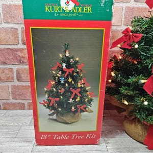 May include: A Christmas tree kit in a box. The box is red, green, and yellow with the text "Holidays Are" and "Santa's World Kurt S. Adler Since 1946". The image on the box shows a decorated 18-inch table tree with red bows and ornaments.