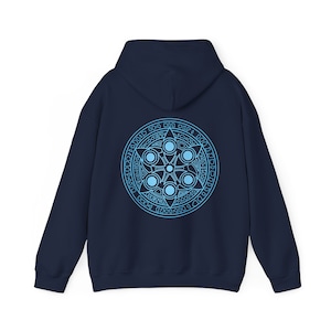 Peut inclure: Un sweat à capuche bleu marine avec un motif bleu clair au dos. Le motif est un symbole circulaire avec une étoile au centre et cinq cercles autour. Le symbole est entouré d'un cercle de texte.