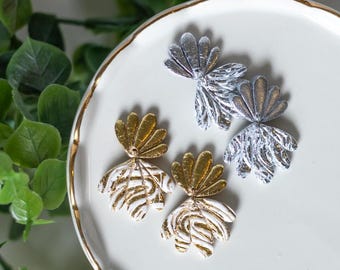 Pendientes de arcilla polimérica metálica dorada o plateada con diseño floral y conchas marinas.