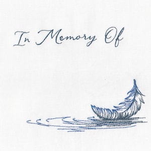 May include: A white card with the text "In Memory Of" in blue cursive script. A blue embroidered feather floats on a blue embroidered water design.