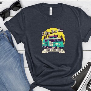 May include: A navy blue t-shirt with a graphic of a teal van with a yellow roof and the text "I Live In A Van Down By The River".