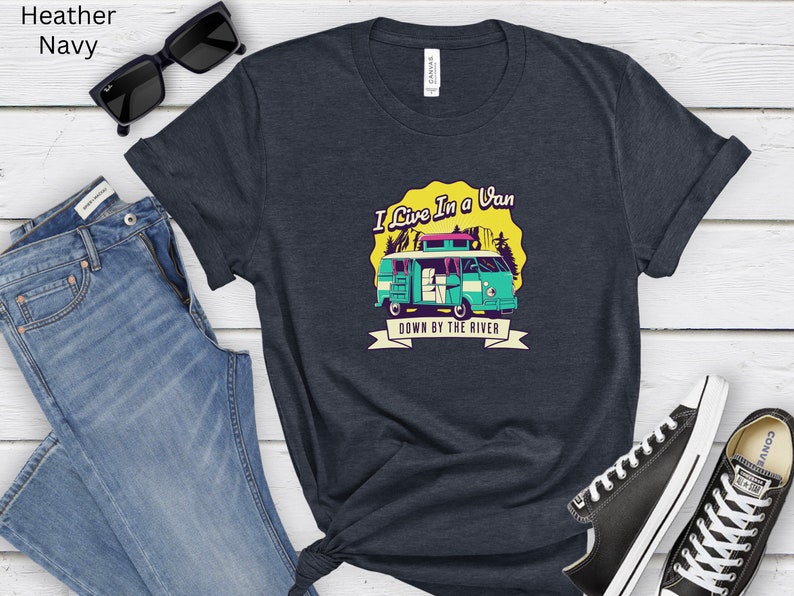May include: A navy blue t-shirt with a graphic of a teal van with a yellow roof and the text "I Live In A Van Down By The River".