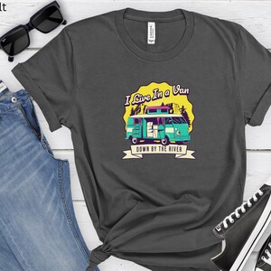 May include: A dark gray t-shirt with a graphic of a teal blue van with the text "I Live In A Van Down By The River".