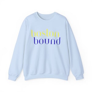 May include: Light blue sweatshirt with the text "boston bound" in yellow and blue lettering.
