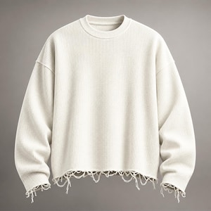 Puede incluir: Un suéter de manga larga en color blanco roto con un patrón de tejido de punto gofrado, cuello redondo y un dobladillo desgastado con hilos sueltos y colgantes a lo largo del borde inferior y los puños, creando un aspecto deshilachado.