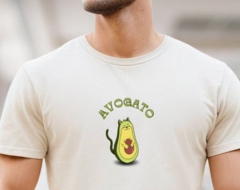 May include: A white t-shirt with a green avocado design. The avocado has a cat face and the text "AVOGATO" above it.