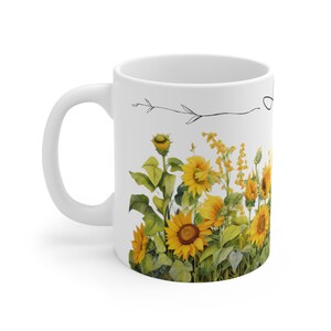 May include: White ceramic mug with a black line drawing of a branch and a field of sunflowers. The sunflowers are yellow with green leaves.