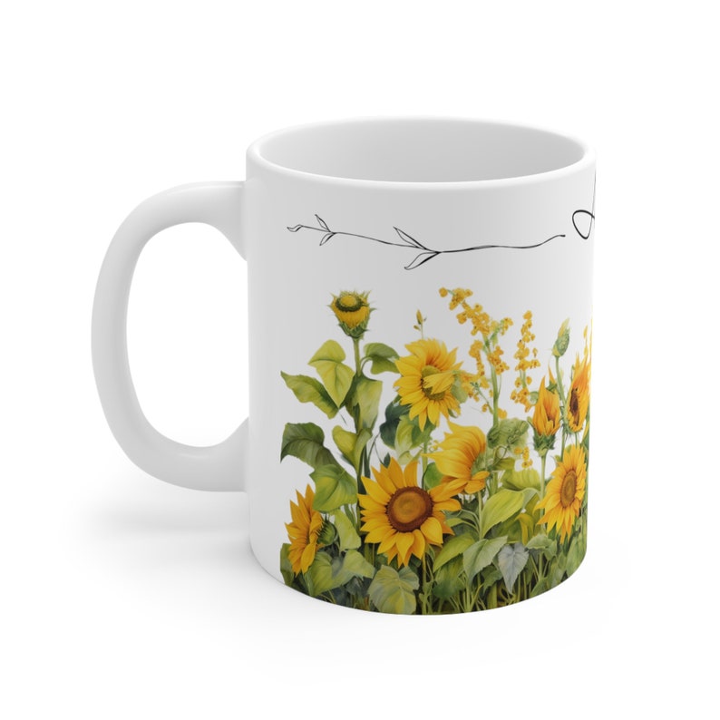 May include: White ceramic mug with a black line drawing of a branch and a field of sunflowers. The sunflowers are yellow with green leaves.