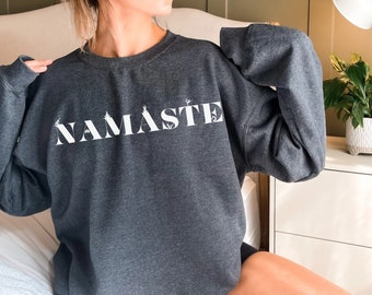 Może przedstawiać: Szara bluza z nadrukiem "NAMASTE" w kolorze białym na przodzie.