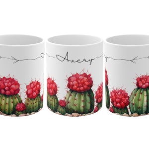 May include: White ceramic mug with a cactus design. The mug features a row of red and green cactus plants with the name "Avery" written on the side.