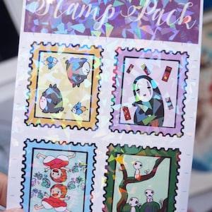 Puede incluir: Una hoja de pegatinas hologr&aacute;ficas con personajes de la pel&iacute;cula de animaci&oacute;n "El viaje de Chihiro". Las pegatinas tienen forma de sellos postales y presentan a Sin Cara, Chihiro y el esp&iacute;ritu del bosque.