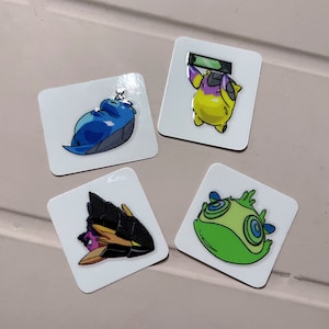 May include: Four square stickers with cartoon illustrations. One shows a blue creature sleeping, another a yellow creature holding a green bar, a third a black and gold creature, and the last a green creature with blue eyes.