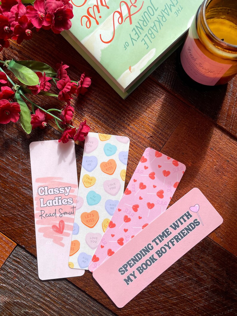 May include: Four decorative bookmarks with different designs and text. One bookmark says "Classy Ladies Read Smut", another features candy hearts, and a third has a pattern of red hearts. The last bookmark says "Spending time with my book boyfriends".