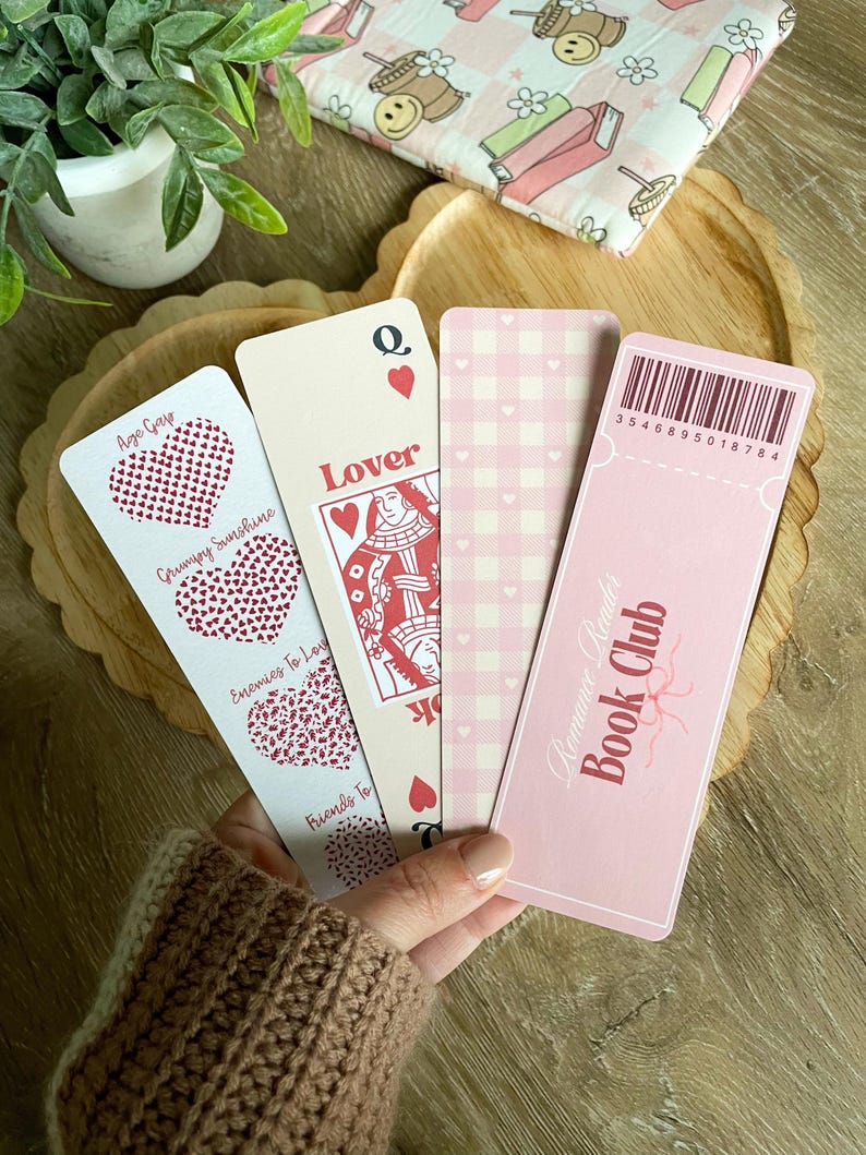 Peut inclure: Quatre marque-pages roses avec des motifs diff&eacute;rents. Un marque-page pr&eacute;sente une carte &agrave; jouer avec la reine de c&oelig;ur et le mot "Lover". Un autre marque-page a un motif vichy rose et blanc. Un troisi&egrave;me marque-page a un motif de c&oelig;ur rose et blanc avec le texte "Age Gap, Grumpy Sunshine, Enemies to Love, Friends to". Le quatri&egrave;me marque-page est rose avec le texte "Romance Reader Book Club" et un code-barres avec le num&eacute;ro "3546895018784".