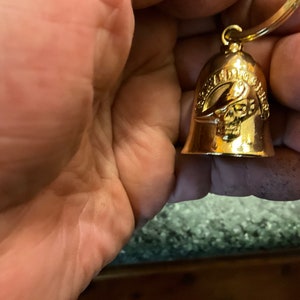 May include: Gold-coloured motorcycle bell keyring with a skull and crossbones design and the text "Harley Davidson" on the side.