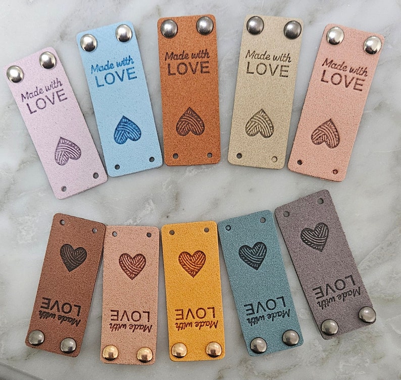 May include: Ten leather labels with a heart design and the text "Made with LOVE" in various colors, including brown, pink, blue, gray, and yellow.