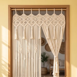 May include: An off-white macrame door curtain featuring intricate knotted patterns, a diamond-shaped top border, and hanging tassels. The curtain is suspended from a wooden rod within a doorway, with one side gathered and tied with a cord.