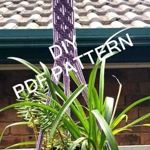 May include: Purple macrame plant hanger with a black pot and green plant hanging from a ceiling. The text "DIY PDF PATTERN" is superimposed on the image.