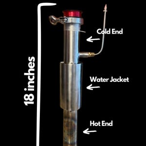 Può includere: Una colonna di distillazione in acciaio inossidabile, alta circa 46 cm, con un tappo rosso e tubi collegati. La colonna è etichettata con i termini "Cold End", "Water Jacket" e "Hot End".