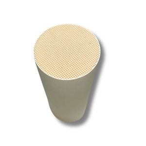 Könnte beinhalten: Ein weißer keramischer Katalysator mit einer Wabenstruktur. Der Katalysator ist so konzipiert, dass er schädliche Emissionen aus dem Fahrzeugabgas reduziert.