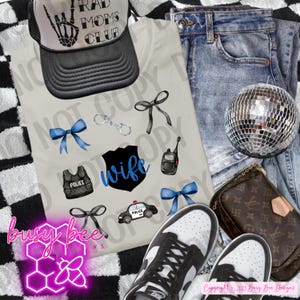 Peut inclure: Un ensemble d'articles comprenant un t-shirt clair avec des graphiques sur le thème de la police, une casquette de camionneur noire et blanche, un jean, des baskets et une boule disco. Le t-shirt présente le mot "wife" et des images liées à la police.