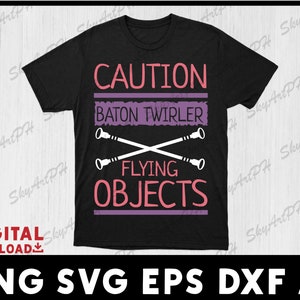 May include: Black t-shirt with a pink and purple design. The text on the shirt reads "Caution Baton Twirler Flying Objects".