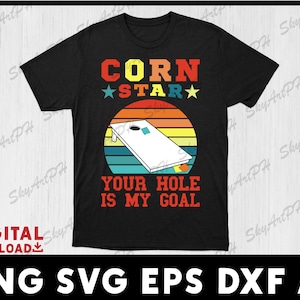 May include: Black t-shirt with a retro-style design featuring a cornhole board and the text "Corn Star Your Hole Is My Goal".