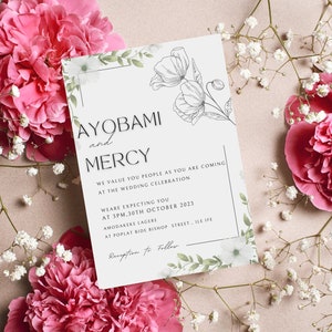 May include: A white wedding invitation with a floral design and the text "AYOBAMI and MERCY" at the top. The invitation includes the date and time of the wedding, as well as the location.