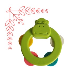May include: Green plastic baby rattle with a hippopotamus face and colorful rings.
