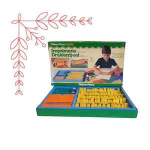 May include: Vintage Fisher-Price Imprimerie Druckerei-Set toy printing set with a blue and green box, yellow letter stamps, and a blue ink pad. The box features a child using the set.