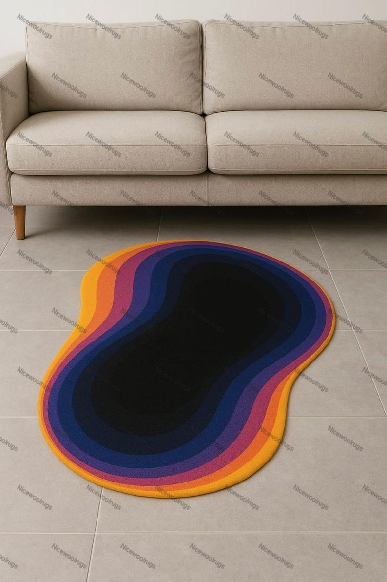 May include: A colorful, abstract rug with a unique shape. The rug features concentric layers of color, transitioning from yellow to orange, purple, and finally, a black center. The rug is placed on a tiled floor in front of a beige sofa.