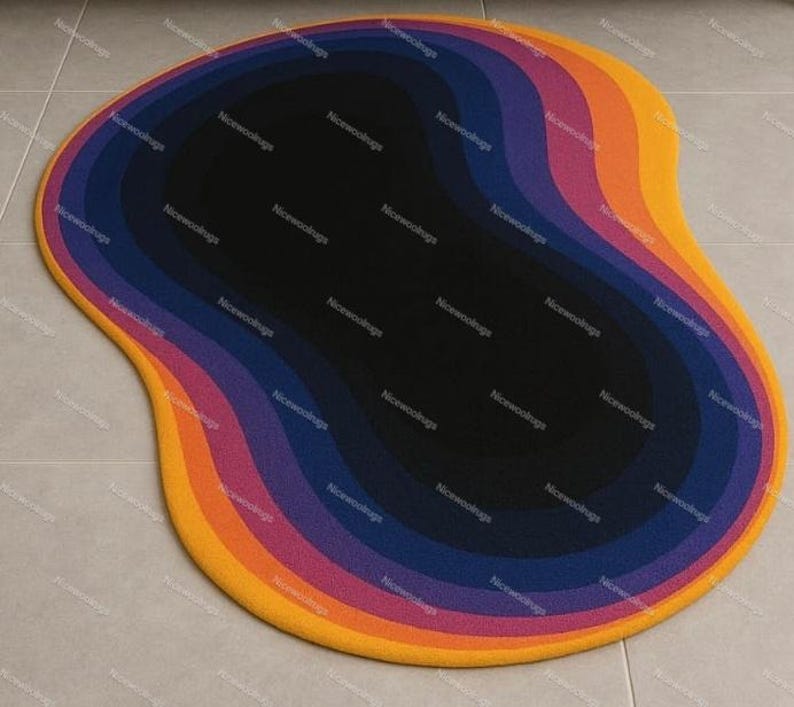 May include: A colorful, abstract area rug with a unique, organic shape. The rug features concentric layers of color, including yellow, orange, pink, purple, blue, and black. The rug is designed to add a modern touch to any room.