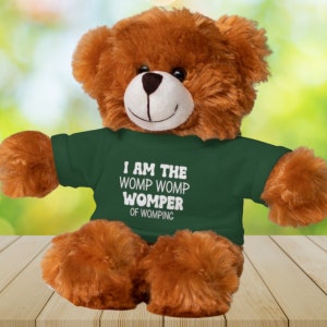 May include: A brown plush teddy bear wearing a green t-shirt with the text "I am the Womp Womp Womper of Womping" in white.