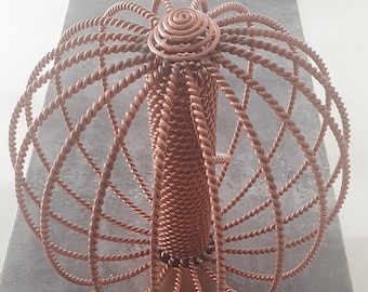 May include: A copper wire sculpture of a tree with a round, twisted top and a cylindrical base.