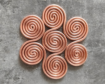 May include: A copper-colored metal coaster with a six-pointed star design made of six interlocking spirals.