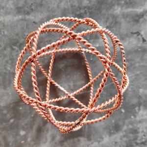 May include: A copper wire sculpture in the shape of a sphere. The wire is twisted and intertwined to create a complex geometric pattern.