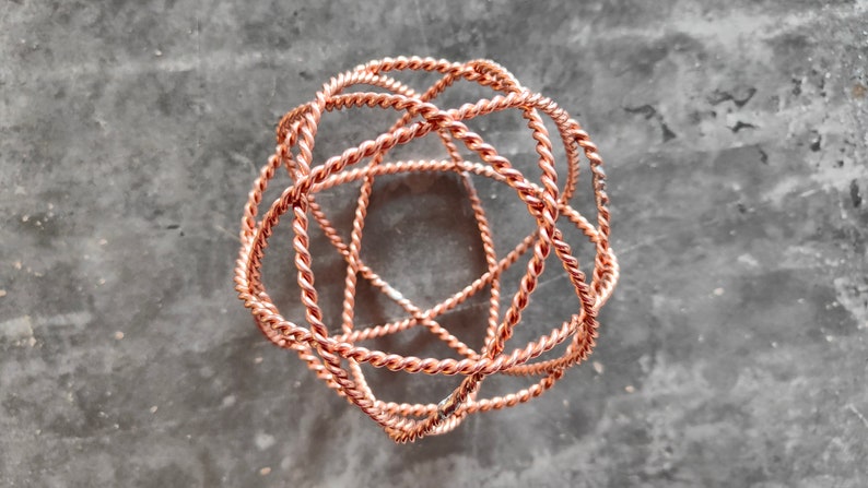 May include: A copper wire sculpture in the shape of a sphere. The wire is twisted and intertwined to create a complex geometric pattern.