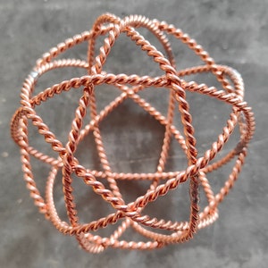May include: A copper wire sphere sculpture with a geometric design. The sphere is made of multiple intertwined wires, creating a complex and intricate pattern.