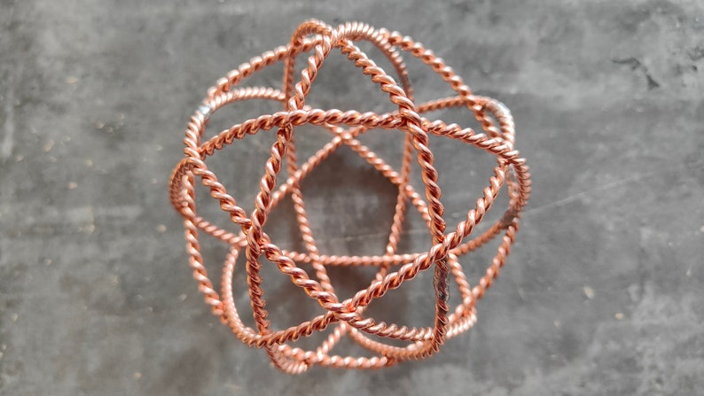 May include: A copper wire sphere sculpture with a geometric design. The sphere is made of multiple intertwined wires, creating a complex and intricate pattern.