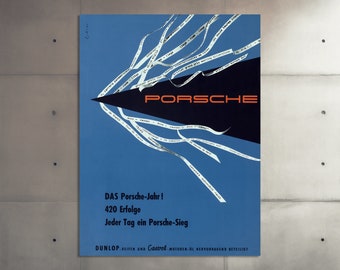 Op de afbeelding: Een blauwe en zwarte vintage poster die reclame maakt voor Porsche met de tekst "DAS Porsche-Jahr! 420 Erfolge Jeder Tag ein Porsche-Sieg DUNLOP REIFEN UND Castrol MOTOREN-OL HERVORRAGEND BETEILIGT".
